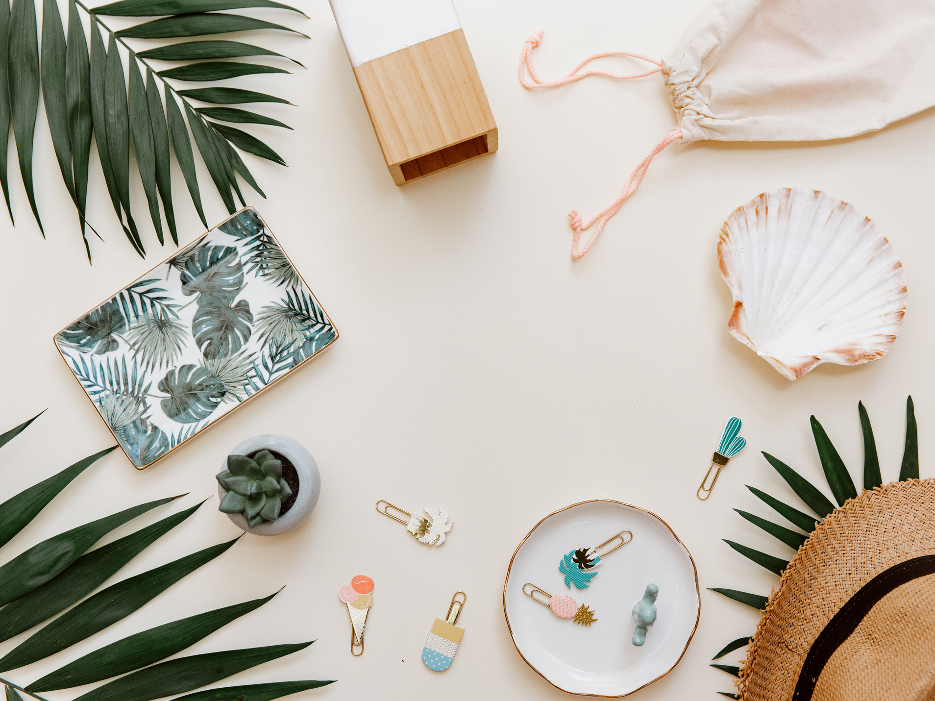 Creative background with tropical leaves and supplies on pastel background. Minimal flat lay, Top view.